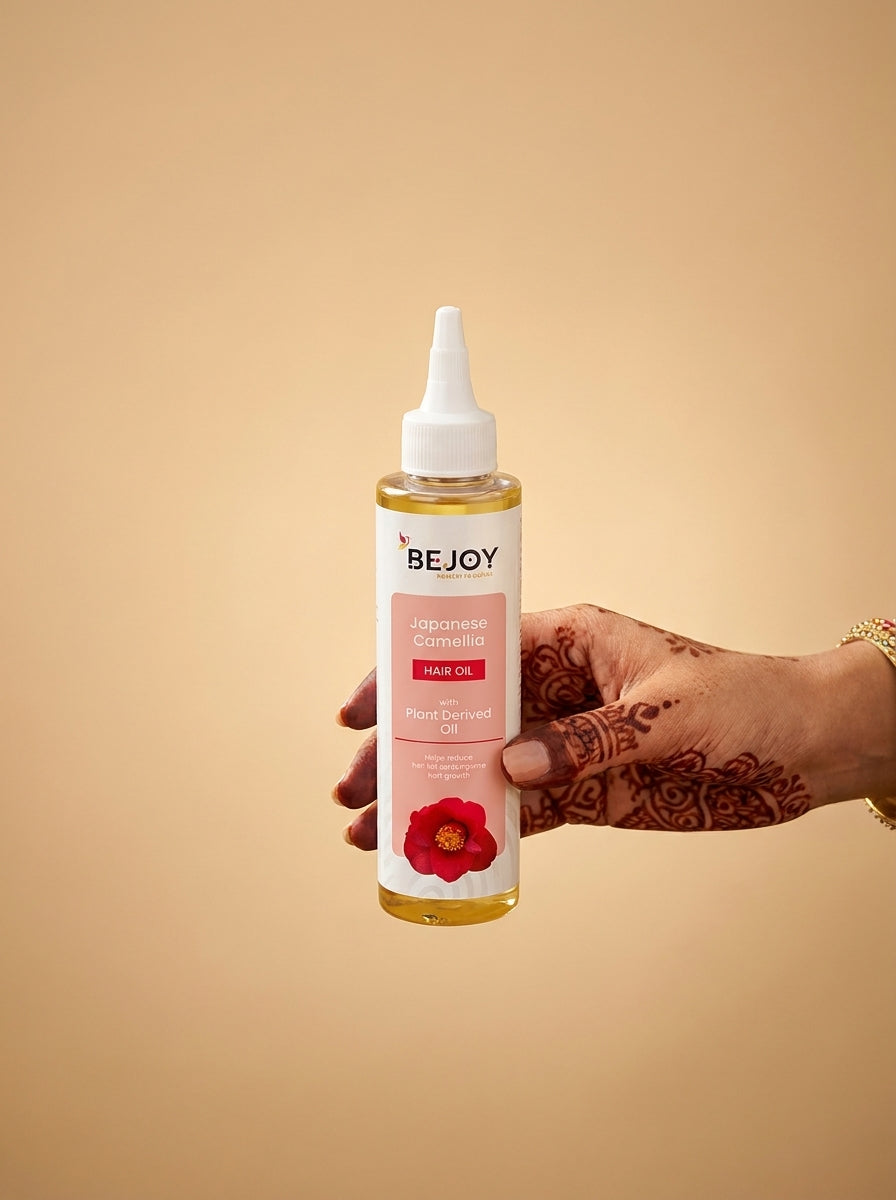 Hand holding a bottle of BEJOY hair oil against a beige background